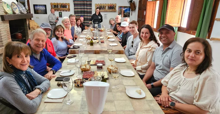 Cruceristas sentados alrededor de una mesa degustando vinos ecológicos y aperitivos locales en la Eco-Bodega Cortijo El Cura, rodeados de un entorno natural en Almería.