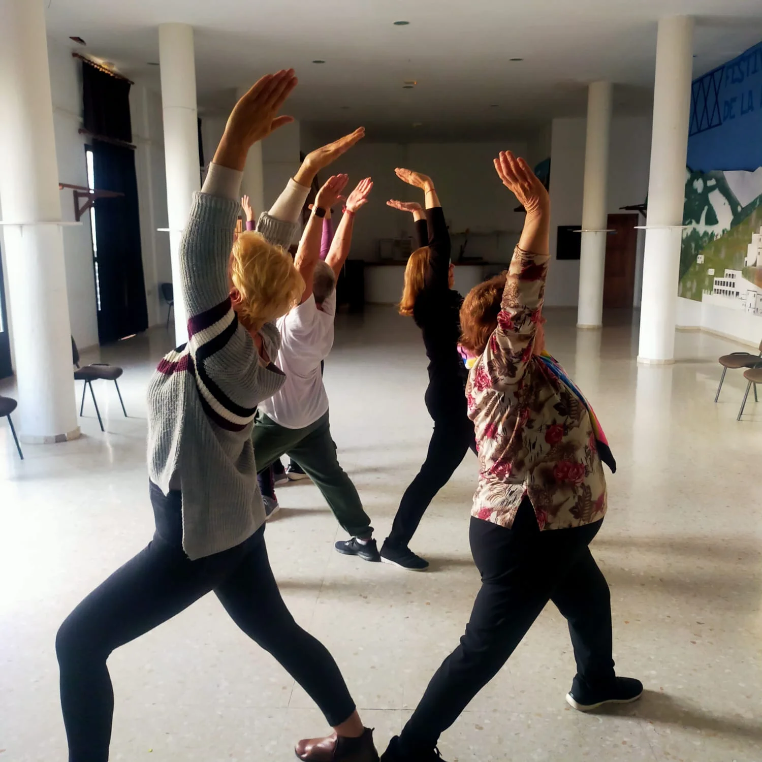 Mujeres practicando yoga con los brazos en alto en una sala junto a viñedos ecológicos en la Alpujarra, junto a la bodega Cortijo El Cura.